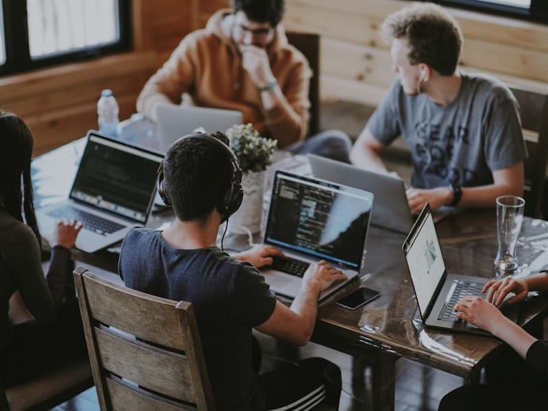 Team collaborating together on laptops at a shared workspace